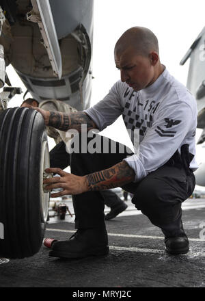 Lo stretto di Singapore (Luglio 6, 2017) DEGLI STATI UNITI Aviazione Navale da elettricista, Mate 2a classe Lucas Mclean, da Arvada, Colo., sostituisce il pneumatico su un F/A-18F Super Hornet da, il "cavalieri neri" di Strike Fighter Squadron (VFA) 154, a bordo della portaerei USS Nimitz CVN (68), 6 luglio 2017, in stretto di Singapore. Nimitz è attualmente sulla distribuzione negli Stati Uniti 7 flotta area di operazioni. Gli Stati Uniti Marina ha pattugliato il Pacifico Indo-Asia di routine per più di 70 anni regionale di promozione della pace e della sicurezza. (U.S. Foto di Marina di Massa lo specialista di comunicazione di terza classe Weston A. Mohr) Foto Stock