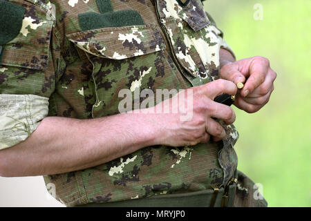 Vista ravvicinata di uomo che indossa maglietta militare proiettili di caricamento Foto Stock