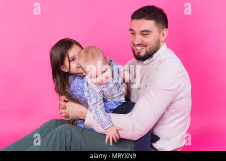 Padre con i bambini che si divertono sull sfondo rosa Foto Stock