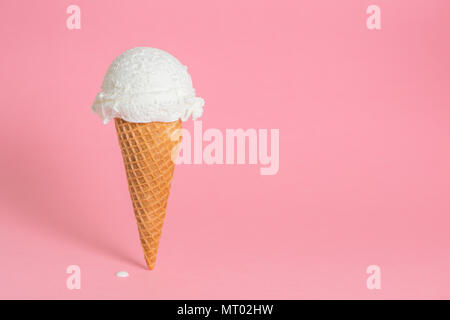 Estate divertente concetto creativo del cono di wafer con ghiaccio fondente crema su sfondo rosa, spazio di copia Foto Stock