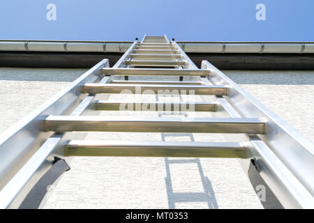 Tre sezione scala in alluminio appoggiata contro la casa Foto Stock