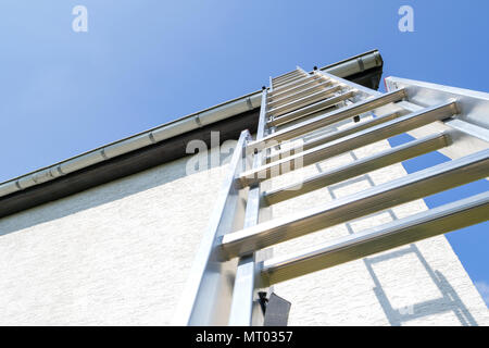 Tre sezione scala in alluminio appoggiata contro la casa Foto Stock