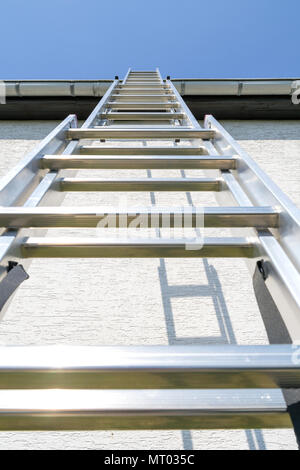 Tre sezione scala in alluminio appoggiata contro la casa Foto Stock