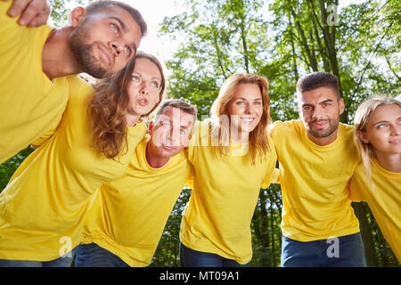 Un gruppo di giovani che abbraccia ogni altra in officina per il lavoro di squadra e spirito di squadra Foto Stock