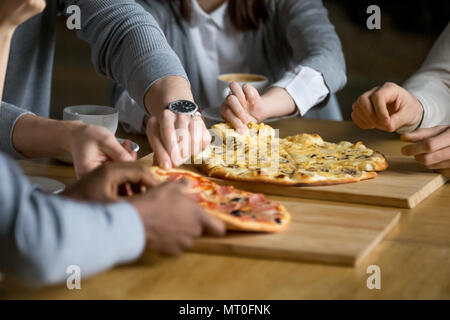 Mani di diverse persone prendendo fette di pizza ristoranti in pizzeria Foto Stock