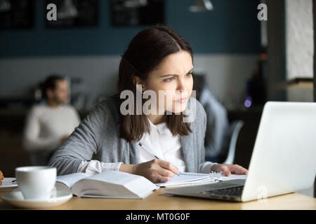 Focalizzato ragazza in questione circa il difficile compito online studiare in c Foto Stock