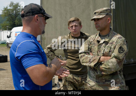 Ron Schultz, con la formazione del team di supporto (TST) Valcea, formazione Expeditionary divisione di assistenza, training di supporto attività Europa, colloqui con gli Stati Uniti Il personale dell'esercito Sgt. Rafael Maldonado, assegnato alla 709th Polizia Militare (MP) Battaglione, XVIII MP brigata, e un soldato britannico, in Ramnicu Valcea, Romania, 20 luglio 2017. TST Valcea offre miglia di attrezzature per le varie nazioni della NATO che parteciperanno a contatto simulato durante un divario umido traversata attraverso il Fiume Olt, come parte dell'esercizio Saber custode. Saber Guardian è un esercizio di multinazionali che si estende attraverso la Bulgaria, l Ungheria e la Romania wit Foto Stock