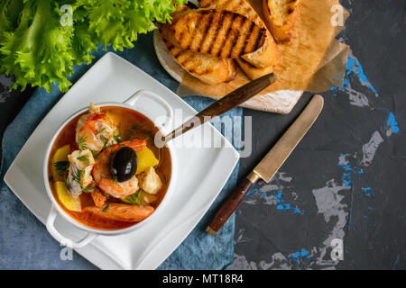 Il francese di una zuppa di pesce bouillabaisse con pesce e frutti di mare, il filetto di salmone e gamberetti, ricchi di sapore, deliziosa cena in un bianco bel piatto. Copia spase Foto Stock