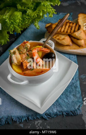 Il francese di una zuppa di pesce bouillabaisse con pesce e frutti di mare, il filetto di salmone e gamberetti, ricchi di sapore, deliziosa cena in un bianco bel piatto. Foto Stock