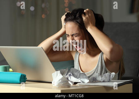 Studente disperato lavorando duro fino a tardi grida nella notte a casa Foto Stock