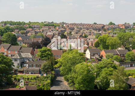 Vista sopraelevata di un quartiere periferico britannico con file di case accoccolate tra lussureggiante vegetazione sotto un luminoso cielo estivo blu Foto Stock