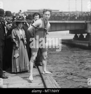 Houdini salti dal ponte di Harvard, 1908, Houdini in piedi dal lato del fiume Charles indossando catene e manette. Harry Houdini (1874 - 1926) austro-ungarico-americano nato Artista della Fuga, l'illusionista e stunt performer Foto Stock