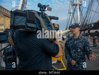 BOSTON (Luglio 23, 2017) marinaio Anthony giorno, assegnato alla USS Constitution, risponde alle domande sulla Costituzione durante un colloquio prima di Old Ironsides risale nell'acqua. Negli ultimi 26 mesi, Costituzione ha subito un esteso intervento di restauro che aiuterà a preservare l'America Nave di stato per molti decenni a venire. (U.S. Foto di Marina di Massa Specialista comunicazione marinaio Casey Scoular) Foto Stock