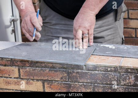 L'installatore le misure e le mette segni per il taglio e la posa di un tile Foto Stock