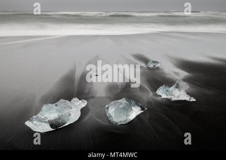 Sabbia nera vulcanica e pezzi di ghiaccio a Breiðamerkursandur beach. Foto Stock