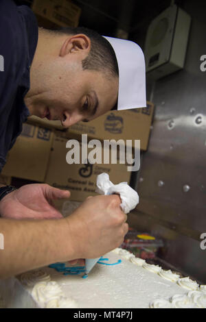 170721-N-AX638-0058 5TH FLOTTA AREA DI OPERAZIONI (21 luglio 2017) specialista culinaria di prima classe Arreguin Eddie, da Los Angeles, decora una torta a bordo del Arleigh Burke-class guidato-missile destroyer USS Howard (DDG 83). Howard è distribuito negli Stati Uniti Quinta Flotta area di operazioni a sostegno della sicurezza marittima operazioni destinate a rassicurare gli alleati e partner e preservare la libertà di navigazione e il libero flusso di commercio nella regione. (U.S. Foto di Marina di Massa lo specialista di comunicazione 2a classe Tyler Preston/rilasciato) Foto Stock