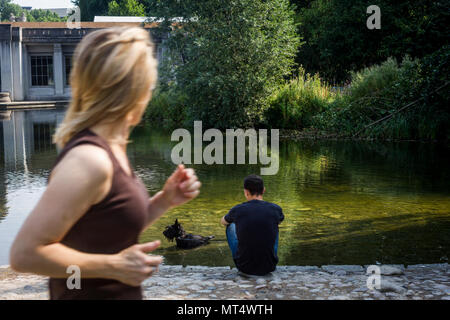 Un runner guarda a un uomo con un cane in Rathaus Schoneberg Park, Berlino, Germania. Foto Stock