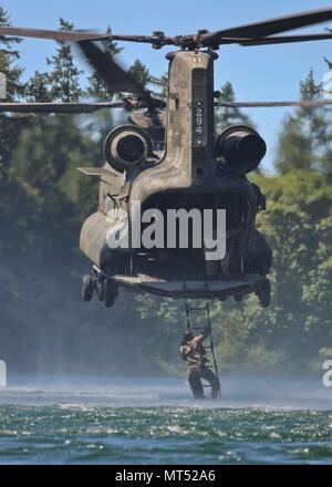 Berretti Verdi assegnato al primo delle forze speciali Gruppo (Airborne) salire una scaletta di corda sospesa da un CH-47 Chinook al lago americano, Base comune Lewis-Mccorda, Washington il 25 luglio 2017. Il training consente di soldati e piloti di provare i loro ruoli in acqua rapida delle operazioni di ripristino. (U.S. Esercito Foto di Sgt. Codie Mendenhall/rilasciato) Foto Stock