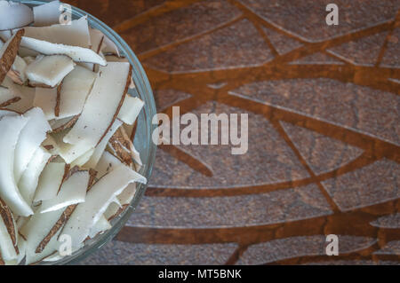 Un trito di noce di cocco in una ciotola su una tavola di legno Foto Stock