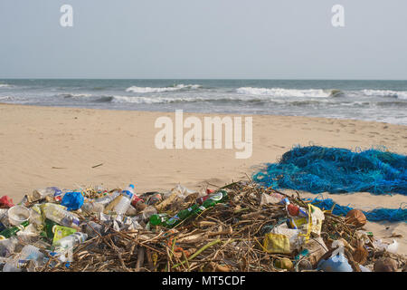 Garbage sulla spiaggia di Goa, India accanto a una rete da pesca. Foto Stock