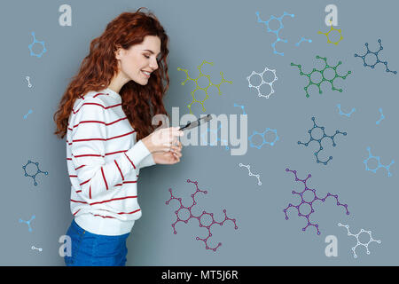 Laboratorio sorridente lavoratore in possesso di una lente di ingrandimento e guardando le catene di cella Foto Stock