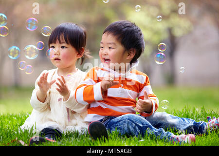 Due piccolo felice asian giochi per bambini all'aperto nel soleggiato parco Foto Stock