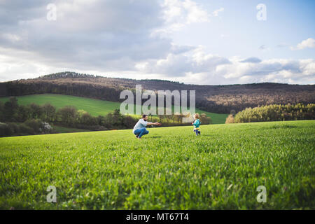 Un padre con suo figlio toddler in esecuzione al di fuori in primavera la natura. Foto Stock