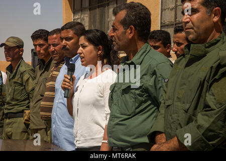 Laila Mustafa, copresidente del Raqqa Consiglio civile, piedi tra Raqqah la sicurezza interna del comandante della forza dell'Idris e i membri del RCC si rivolge a laureati di classe RISF 005 prima di laurearsi la loro formazione in Ayn Issa, Siria, 31 luglio 2017. Dopo la laurea, i 232 nuovi membri RISF dovranno distribuire alle aree protette di Raqqah cancellata di Iside militanti. (U.S. Esercito Foto di Sgt. Mitchell Ryan) Foto Stock