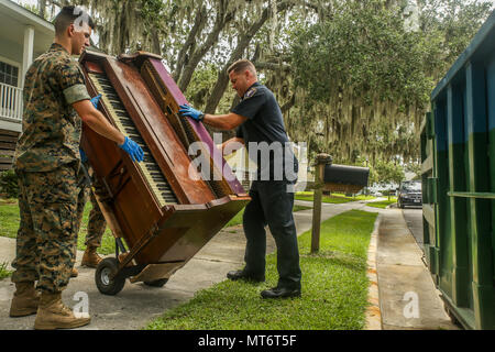 Polizia militare trasportare un pianoforte da una casa danneggiata da un incendio di un cassonetto a bordo Marine Corps reclutare Depot Parris Island, luglio 27. Marines e civili con il prevosto Maresciallo dell'Ufficio si è offerto volontariamente il loro tempo per aiutare una famiglia nel bisogno come parte della loro missione di proteggere e servire. La polizia militare sono con la sede centrale di PMO e sede Squadron, Marine Corps Air Station Beaufort. Foto Stock