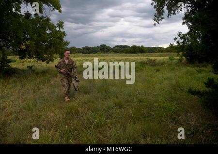 Tech. Sgt. Garrett Wright, XXII Operations Support Squadron sopravvivenza, Evasione, di resistenza e di fuga e di personale specializzato di recupero, passeggiate attraverso un campo mentre si conduce una lotta contro la sopravvivenza Corso di Aggiornamento Luglio 13, 2017, in Derby, Kan. Wright conduce vari tipi di sere formazione per gli avieri a McConnell Air Force Base. (U.S. Air Force foto/Airman 1. Classe Erin McClellan) Foto Stock