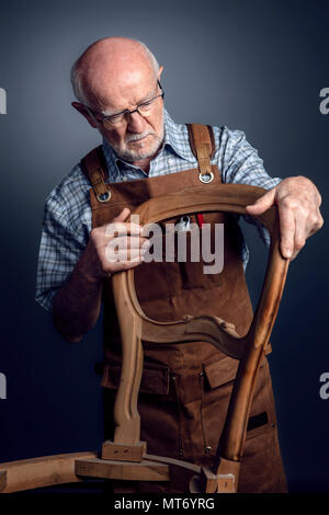 Senior artigiano caucasica controllare sedia incompiuto studio shot Foto Stock