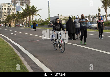 Arabia donna in nero abaya in sella ad una bicicletta in Jeddah Arabia saudita sulla nuova pista per la corsa in Corniche Foto Stock