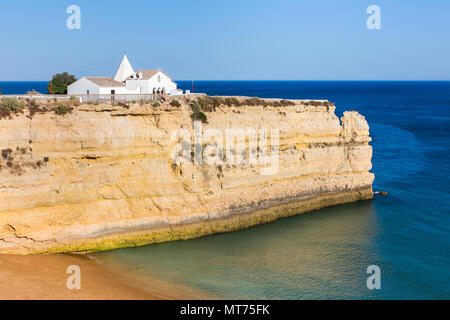 Di piccole dimensioni e di colore bianco chiesa portoghese sulla roccia ripida nel blu del mare Foto Stock