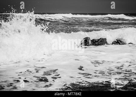 Crashing Choas come le onde si infrangono tra le rocce in mare Foto Stock