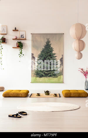 Vista frontale del flip-flop in un asiatico sala da pranzo interno con un grafico ad albero sulla parete, il futon e un lampadario Foto Stock