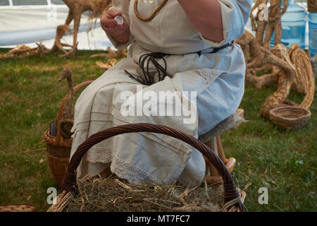 Donna in abiti tradizionali di fare artigianato con erba secca e paglia in un vicino la vista ritagliata Foto Stock