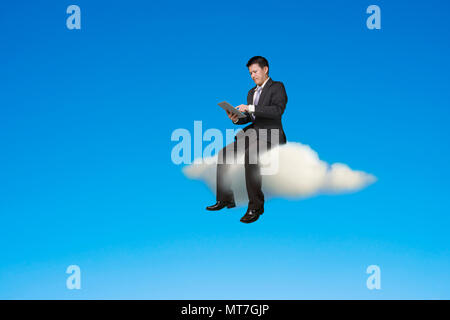 Imprenditore con tavoletta digitale e seduto sulla nuvola nel cielo dello sfondo. Foto Stock