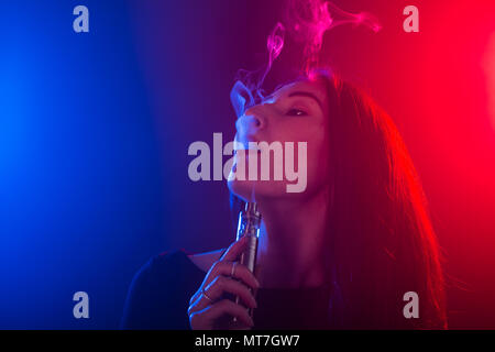 Giovane donna di fumare sigaretta elettronica Foto Stock