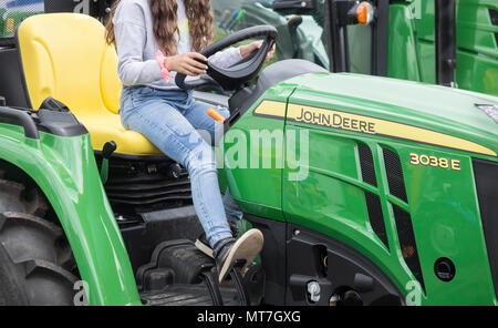 Giovane donna al volante di un John Deere 3038E. trattore Foto Stock