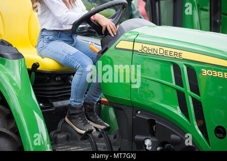 Giovane donna al volante di un John Deere 3038E. trattore Foto Stock