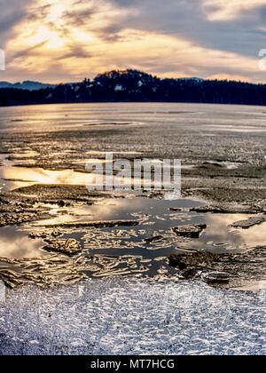 Shining iceberg e ice floes, ghiaccio crepacci raggi riflessi nell'acqua liscia superficie. Punteruolo di ghiaccio in laguna. Foto Stock