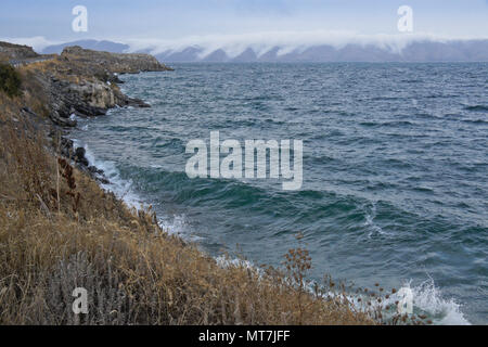 Nuvole cascata giù per le colline che circondano il Lago Sevan in Armenia in una giornata particolarmente ventosa in autunno Foto Stock
