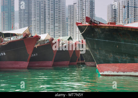 Commerciale barche da pesca allineate sul porto di Hong Kong con hi-rise in background Foto Stock