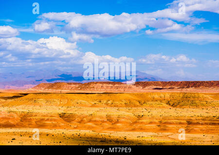 Il pittoresco paesaggio con dune di sabbia arancione e montagne del deserto del Sahara con un luminoso cielo blu e nuvole in Marocco Foto Stock