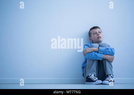 Lonely bambino autistico seduto su un pavimento di una stanza Foto Stock