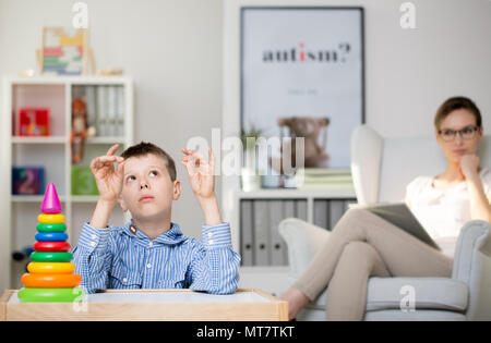 Professional psicologo osservando un ragazzo autistico nel suo ufficio Foto Stock