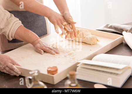 Le donne preparare un impasto per pizza sulla spianatoia in cucina Foto Stock