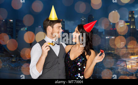 Coppia felice con party soffianti divertendosi Foto Stock