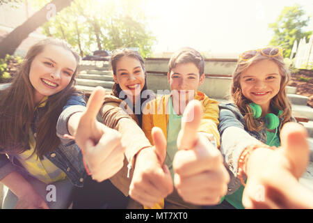 Amici di adolescenti o studenti mostrando pollice in alto Foto Stock