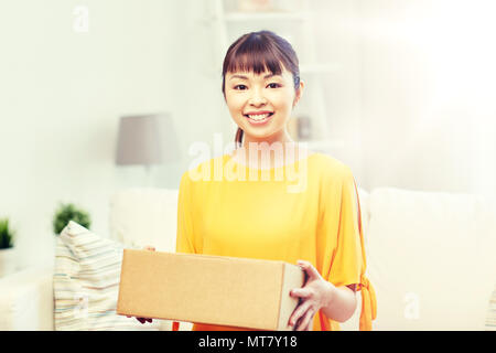 Felice asian giovane donna con casella di pacchi a casa Foto Stock